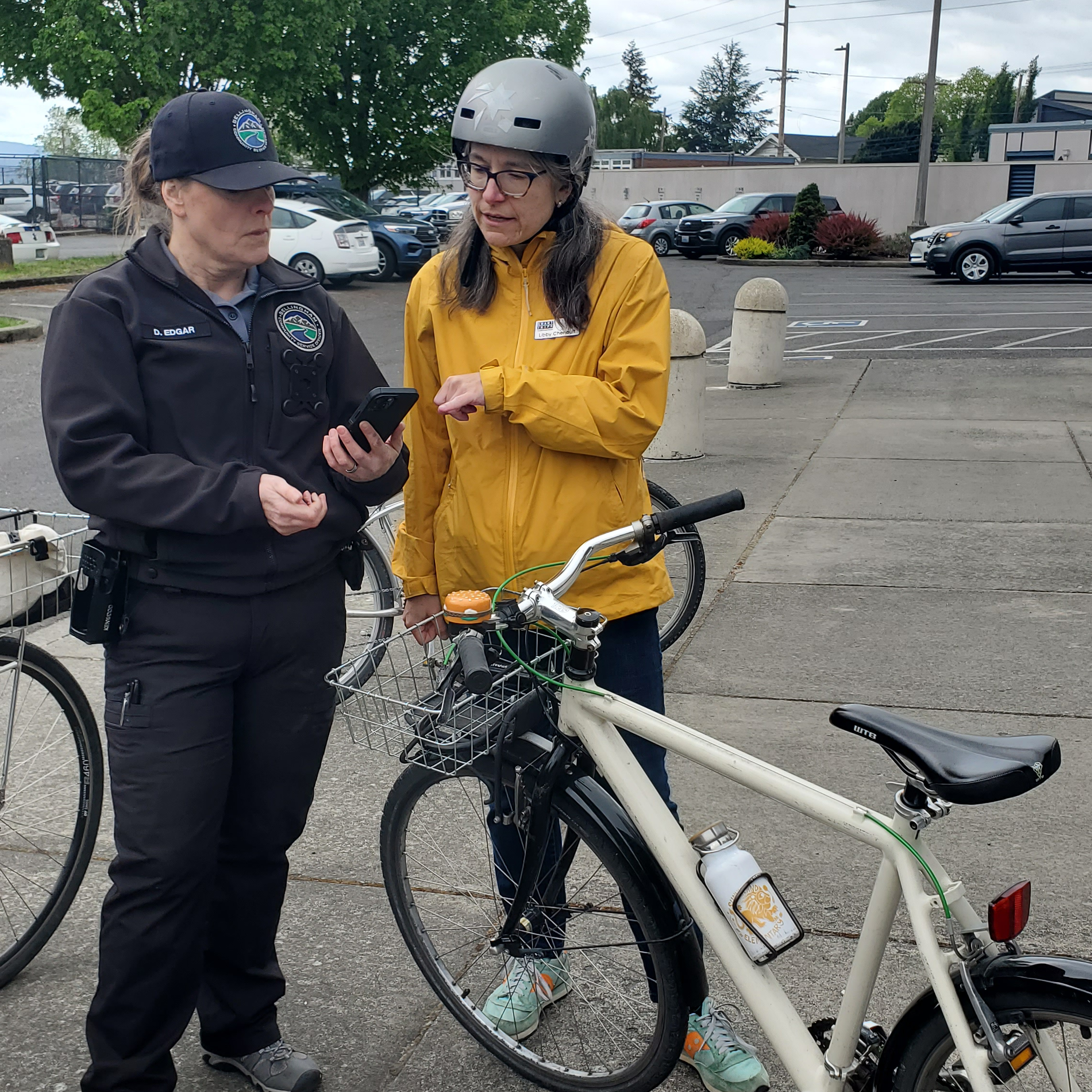 A police officer is taking to a person about registering their bicycle, white bike in foreground.
